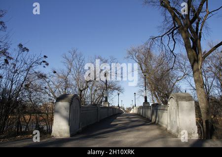 Pont à pied traversant la rivière Assiniboine avec des arbres en hiver, parc Assiniboine, Winnipeg, Manitoba, Canada Banque D'Images