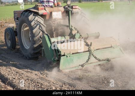 un jeune agriculteur sur son tracteur enveloppé de poussière préparant le sol pour la nouvelle récolte Banque D'Images