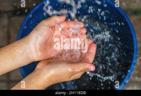 L'eau coule dans les mains de l'enfant.Mise au point sélective.Enfant. Banque D'Images