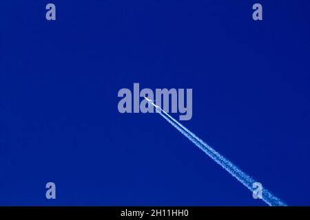 L'avion et le panache des gaz d'échappement blancs de lui contre le ciel bleu. Banque D'Images
