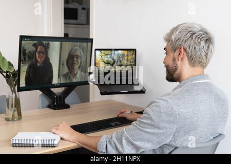 Jeune homme hipster ayant des appels vidéo avec ses collègues à l'aide de l'application informatique - vidéo d'entreprise multi-générationnelle Banque D'Images