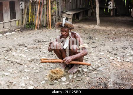 Wamena, Indonésie - 9 janvier 2010 : l'homme de la tribu Dani dans une robe traditionnelle allume le feu.Indonésie Nouvelle Guinée Banque D'Images