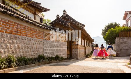 Trois jeunes femmes dans des hanboks colorés marchant dans la rue dans le village de Bukchon Hanok à Séoul. Banque D'Images