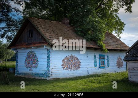 Zalipie, Pologne - 1er août 2021 : chalet traditionnel en bois blanc, avec murs peints dans un motif floral coloré. Banque D'Images