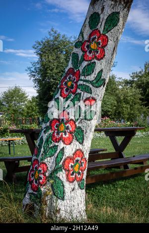 Zalipie, Pologne - 1 août 2021 : tronc d'arbre peint en motif floral coloré.Ensoleillé, jour d'été. Banque D'Images