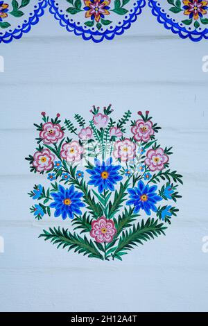 Zalipie, Pologne - 1 août 2021 : un motif floral coloré, peint sur un mur en bois blanc. Banque D'Images