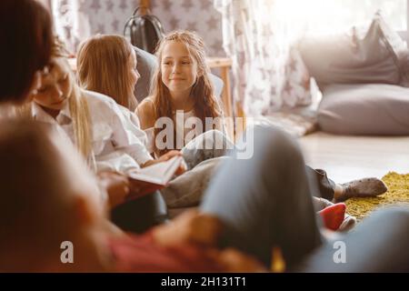 Des filles souriantes bavardent pendant une leçon à l'école Banque D'Images