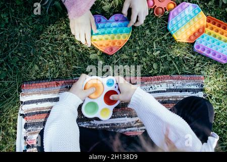 Enfants jouant avec des jouets pop IT sur l'herbe verte Banque D'Images