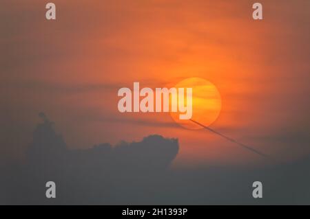 Sun disque à travers les nuages au coucher du soleil au-dessus de l'horizon.France. Banque D'Images