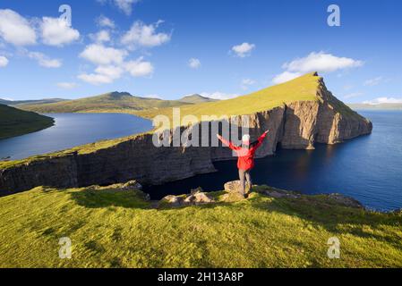 Un touriste dans une veste rouge bénéficie de la vue sur le lac Leitisvatn ou Sorvagsvatn sur l'île de Vagar, îles Féroé Banque D'Images