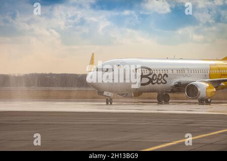 Avion jaune de la compagnie aérienne Bees sur le tablier.Boeing 737-800 UR-UBA avion de tourisme.Après la pluie et le lavage.Copier piste d'espace.Ukraine, Kiev - 19 mars 2021. Banque D'Images