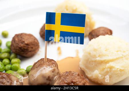 Boulettes de viande aux pommes de terre bouillies et sauce rouge douce décorées par le drapeau suédois - plat suédois traditionnel Banque D'Images