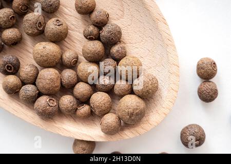 Gros plan de l'épice, des grains d'épice ou du poivre noir sur une cuillère en bois.Poivre dispersé, vue du dessus Banque D'Images