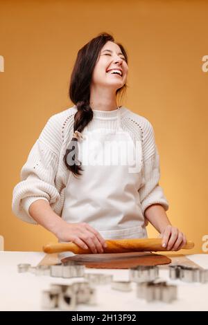 Une femme en train de rire fait rouler la pâte avec un rouleau. Banque D'Images