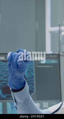 Spécialiste en chimie analysant des échantillons de sang sur verre en laboratoire. Femme technicien avec des lunettes et des gants portant une blouse de laboratoire tout en tenant l'instrument avec du plasma pour le diagnostic médical Banque D'Images