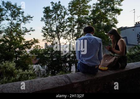 Paris, France - juillet 2019 : jeune couple français assis sur un parapet à la place du Calvaire à Montmatre, bénéficiant d'une vue sur Paris.Il est proche Banque D'Images