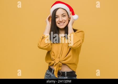 Photo d'une jolie femme dans un chapeau de Noël.Porte une chemise jaune, un arrière-plan isolé de couleur jaune Banque D'Images