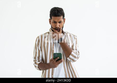 Portrait d'homme barbu en colère utilise des écouteurs sans fil et mains libres. Banque D'Images