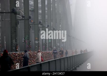 Cologne, Allemagne.16 octobre 2021.Les randonneurs traversent le pont Hohenzollern dans le brouillard.Credit: Oliver Berg/dpa/Alay Live News Banque D'Images