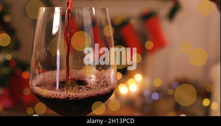 Image de taches brillantes sur un verre de vin rouge et de décorations de noël Banque D'Images