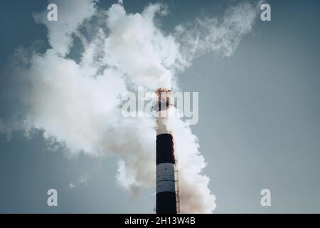 Le tuyau rayé de la plante, émettant de la fumée nocive pour l'environnement dans le ciel bleu.Porter préjudice à l'écologie de la terre.Émissions nocives. Banque D'Images