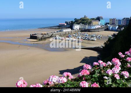 Vue sur le port de Tenby à marée basse.Les anciennes et les nouvelles stations de sauvetage sont visibles à gauche de la colline du château.Les gens s'amusent à marcher sur le sable. Banque D'Images