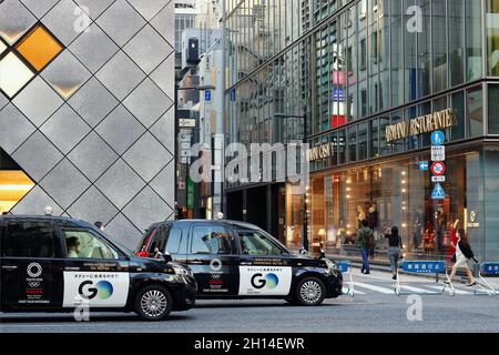 TOKYO, JAPON - 14 octobre 2021 : rue dans la région de Ginza à Tokyo avec des magasins Bottega Veneta et Emporio Armani et des taxis portant les logos olympiques de Tokyo. Banque D'Images
