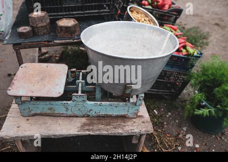 Image de faible profondeur de champ (foyer sélectif) avec de vieux poids à l'échelle sur la table d'un paysan roumain vendant des légumes de son jardin dans une zone rurale Banque D'Images