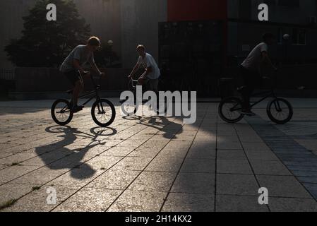 Silhouette de gars sur les vélos BMX dehors contre le coucher du soleil.Les jeunes sont engagés dans le sport actif.FreeStyle BMX. Banque D'Images
