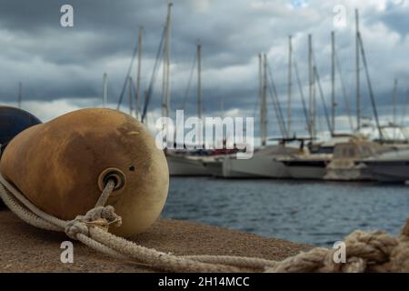 Gros plan d'une boule en plastique dans un port et en arrière-plan, hors foyer, une marina sur l'île de Majorque, dans un coucher de soleil nuageux Banque D'Images