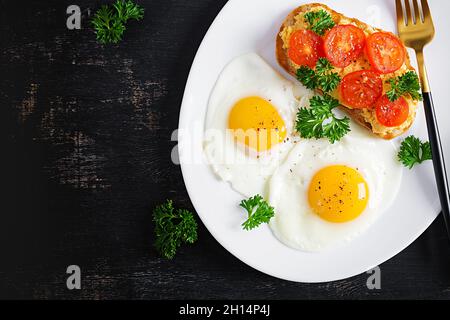 Des œufs frits et un sandwich au pâté de poulet grillé sur fond sombre.Vue de dessus, au-dessus de la tête Banque D'Images