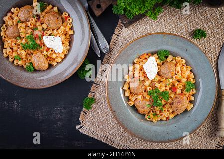 Pâtes italiennes traditionnelles dalitini avec boulettes de viande dans une sauce tomate et légumes dans un bol.Pâtes Ditalini et boulettes de bœuf avec sauce tomate à la marinara. Banque D'Images