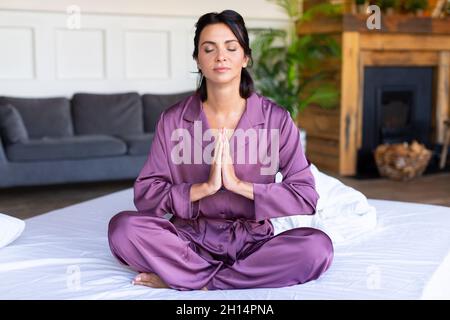 Belle femme d'âge moyen méditant sur le lit.Concept de santé mentale. Banque D'Images