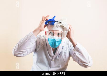 Médecin choqué avec les mains sur son avait dans le masque médical de protection et le manteau blanc de laboratoire isolé Banque D'Images