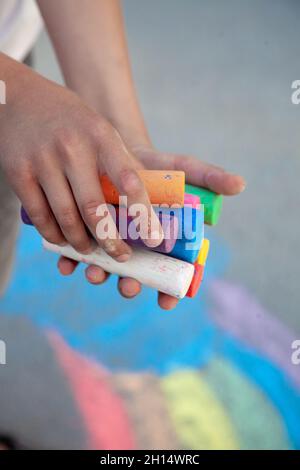 Craies. Grands crayons multicolores dans les mains des enfants. L'enfant tient la craie. Dessinez sur la rue. Dessin fascinant pour les enfants. Copier l'espace. Banque D'Images