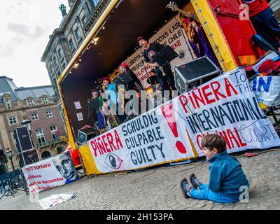 Un petit garçon est vu assis sur le sol tout en regardant la représentation d'un groupe chilien pendant la démonstration .À l'occasion du deuxième anniversaire de l'épidémie sociale chilienne, plusieurs organisations européennes de défense des droits sociaux, politiques et humains se sont réunies pour exiger la vérité, la justice, la réparation et des garanties de non-répétition pour les violations systématiques des droits de l'homme commises par des policiers chiliens, approuvées par le président sortant du Chili, Sebastian Piñera.À Amsterdam, la communauté chilienne a organisé une manifestation accompagnée de spectacles et de musique chilienne dans le centre o Banque D'Images