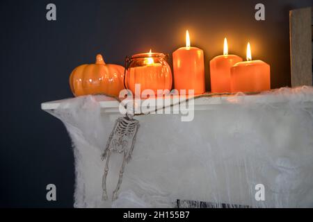 Décoration de la maison d'Halloween.Squelettes de jouets en plastique dans une boîte en bois sur une cheminée contre un mur bleu foncé.Une guirlande de squelettes.Cobweb sur le dresse Banque D'Images