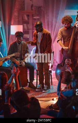 Un jeune homme africain chantant pendant que son groupe joue sur des instruments lors d'une représentation au club Banque D'Images