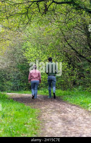 un jeune couple se promenant ensemble à travers les bois ou la forêt le long d'une piste ou d'un sentier arborescent à travers la forêt.Jeune couple marchant dans les bois ensemble Banque D'Images