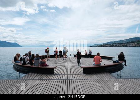 Les touristes se détendant sur la plate-forme circulaire sur Mer donne sur le lac Léman juste à côté de la statue de Freddie Mercury à Montreux Riviera, Suisse Banque D'Images