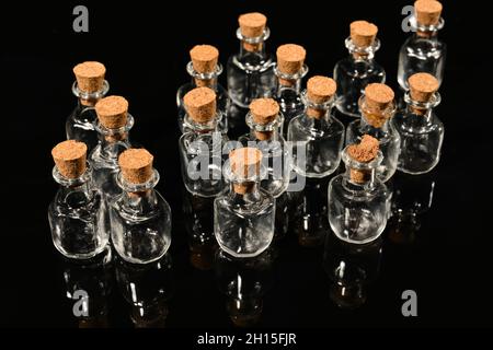 Flacons en verre avec liège sur une surface miroir noire avec réflexions isolées sur fond noir Banque D'Images