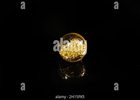 perles avec paillettes dorées sur fond noir miroir Banque D'Images