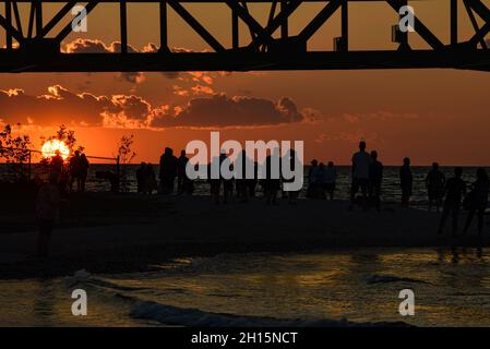 Les touristes se rassemblent sous le pont Mackinac, l'un des plus longs ponts au monde au-dessus du détroit de Mackinac, au coucher du soleil, Mackinaw City, Michigan, États-Unis Banque D'Images
