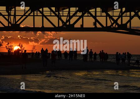Les touristes se rassemblent sous le pont Mackinac, l'un des plus longs ponts au monde au-dessus du détroit de Mackinac, au coucher du soleil, Mackinaw City, Michigan, États-Unis Banque D'Images