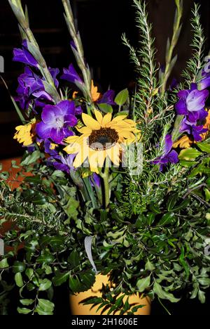 arrangement avec fleurs du soleil, gladiola et verts dans vase jaune Banque D'Images