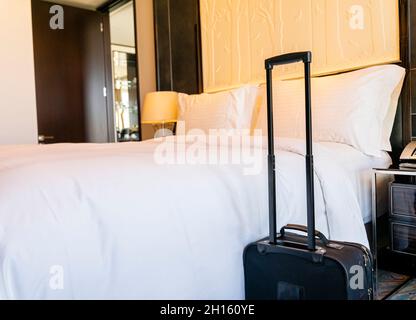 Valise à bagages à côté du lit king size fraîchement préparé dans une suite avec chambre d'hôtel Banque D'Images