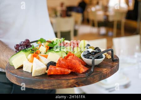 Serveur tenant une planche en bois avec hors-d'œuvre servi dans l'espace de copie du restaurant Banque D'Images