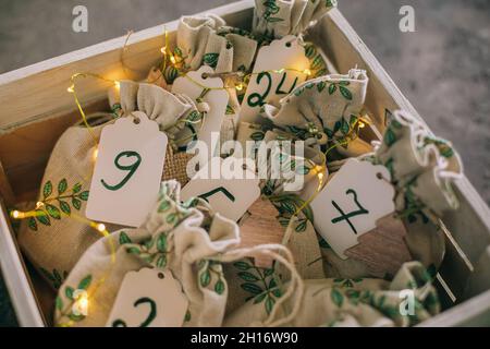 Calendrier original de l'Avent de noël pour les enfants.Des cadeaux pour les enfants s'amusent dans des sacs en tissu dans une boîte en bois. Banque D'Images