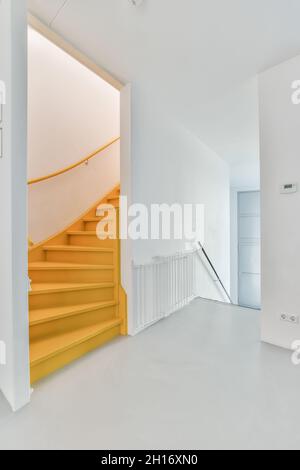 Escalier vide ondulé contre hall avec clôture et murs blancs dans une maison lumineuse contemporaine Banque D'Images