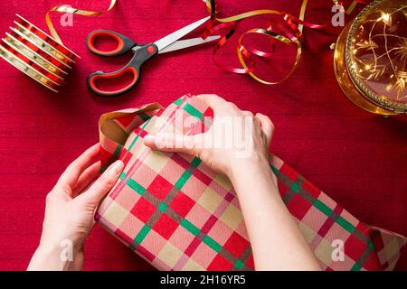 La famille se prépare pour Noël.Vue de dessus des mains emballer des cadeaux.Boîtes avec cadeaux, papier d'emballage coloré, ciseaux et rubans. Banque D'Images